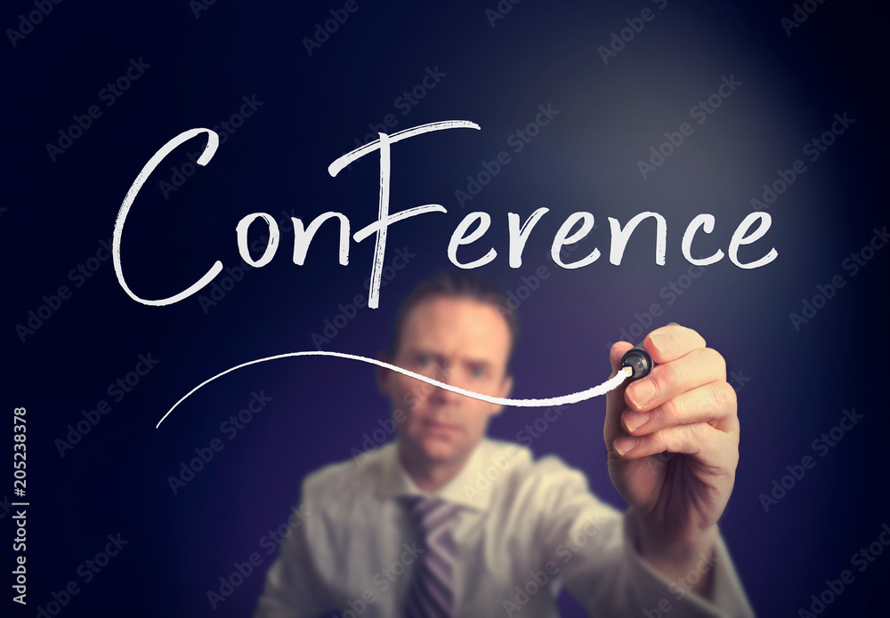 A businessman writing a Conference concept with a white pen on a clear screen. A businessman writing a Conference concept with a white pen on a clear screen.