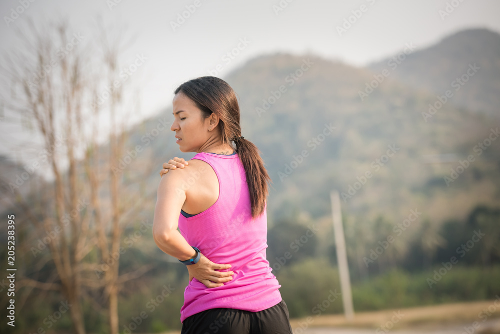 Neck pain during training. Athlete running woman runner with sport injury rubbing and touching upper back muscles outside after exercise workout in summer. Neck pain during training. Athlete running woman runner with sport injury rubbing and touching upper back muscles outside after exercise workout in summer.