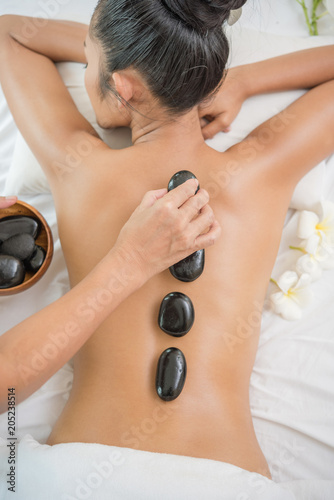 Young woman getting hot stone massage in spa salon. Beauty treatment concept.
