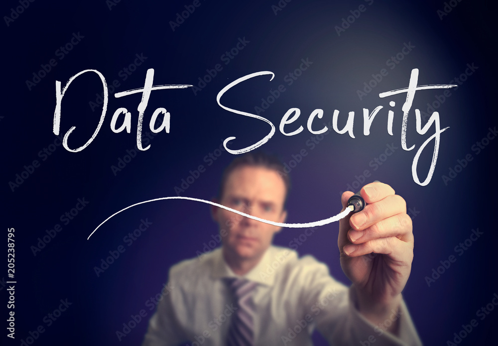 A businessman writing a Data Security concept with a white pen on a clear screen. A businessman writing a Data Security concept with a white pen on a clear screen.