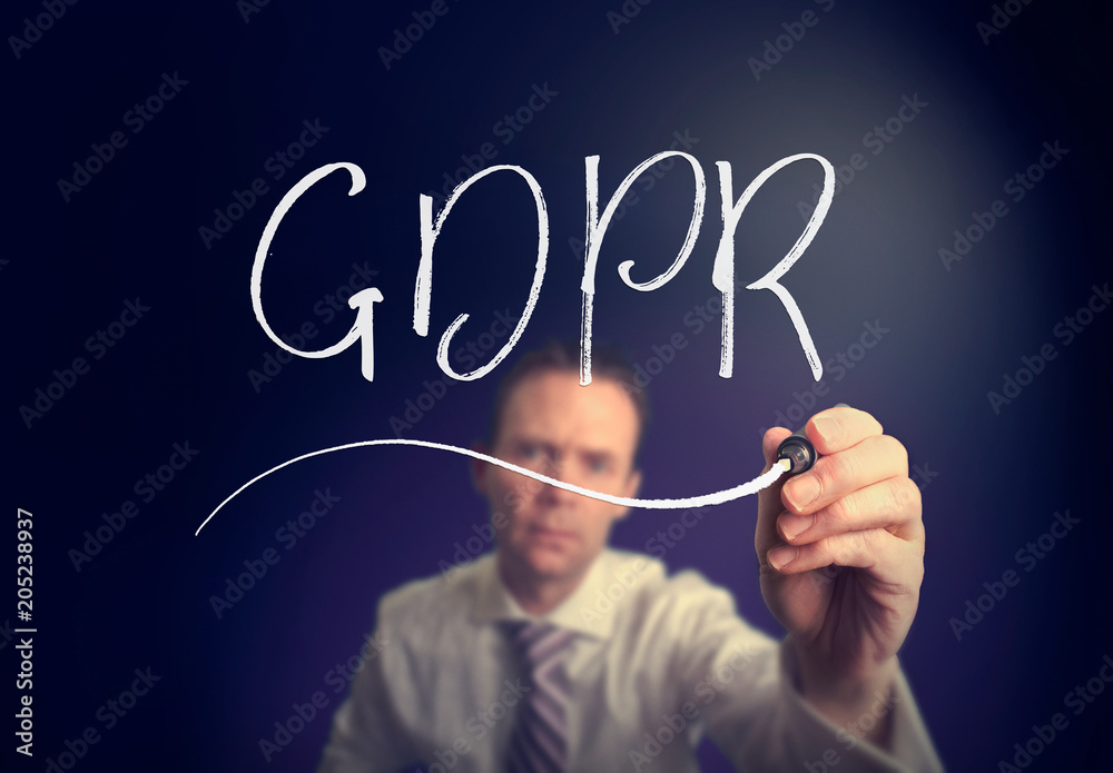 A businessman writing a GDPR concept with a white pen on a clear screen. A businessman writing a GDPR concept with a white pen on a clear screen.