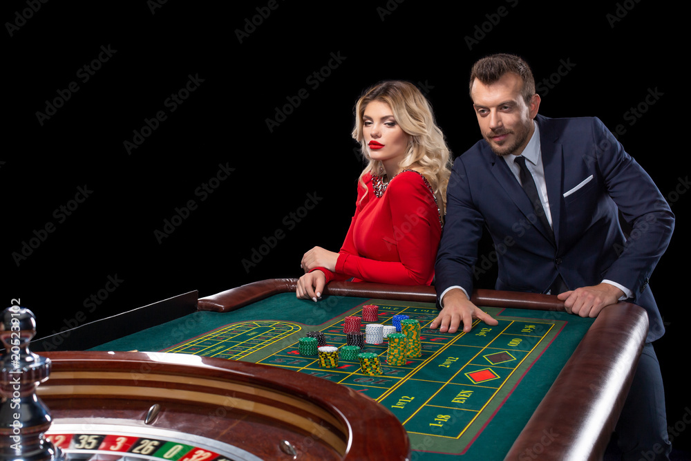 Beautiful and well dressed couple playing roulette in the casino Beautiful and well dressed couple playing roulette in the casino