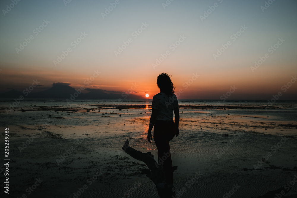 .Young woman on vacation in the Gili Islands enjoying a colorful sunset in Indonesia. Photograph and vacation.