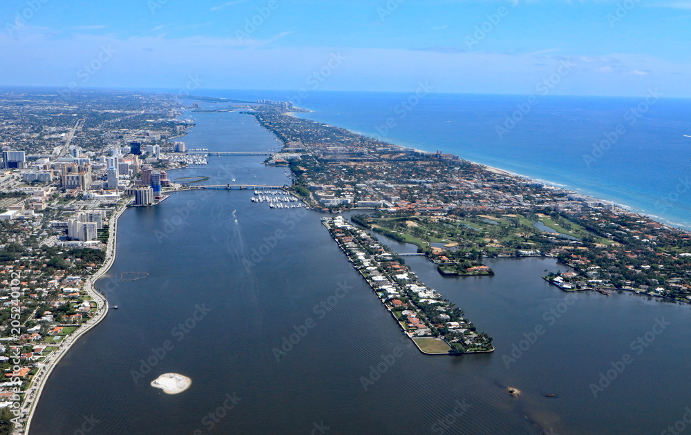 Aerial view downtown West Palm Beach, Florida, and the island of Palm Beach, with the Lake Worth Lagoon separating the two.