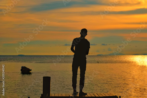 a silhouette of fishing man with fishing rod at the sunset time.