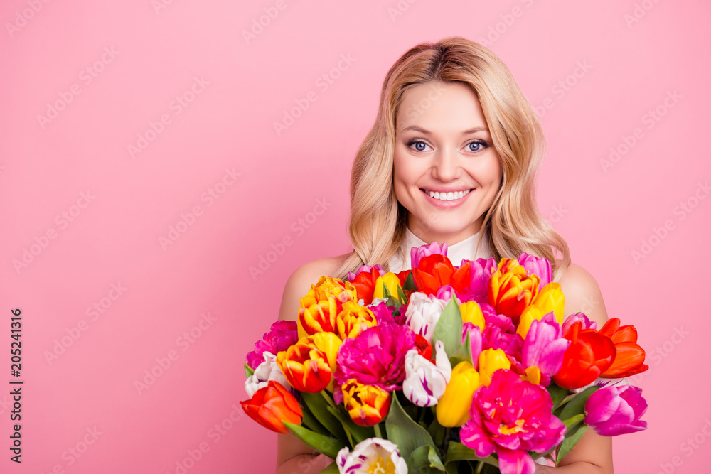 Portrait with copyspace, empty place of pretty wife, charming mother, cheerful positive woman holding big bouquet of colorful tulips in hands isolated on pink background looking at camera Portrait with copyspace, empty place of pretty wife, charming mother, cheerful positive woman holding big bouquet of colorful tulips in hands isolated on pink background looking at camera