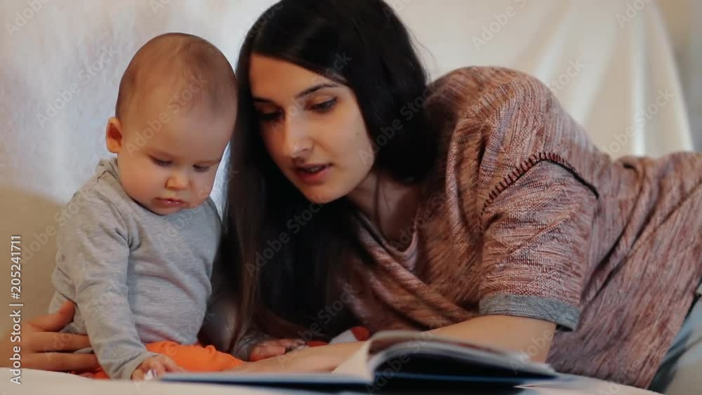 A young mother and a small child reading a book. Slow motion shot. A young mother and a small child reading a book. Slow motion shot.
