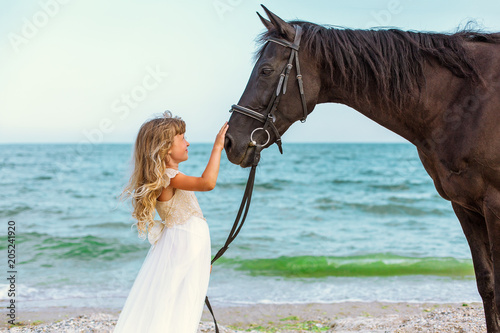 little girl with horse by the sea
