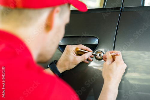 locksmith opening car door with lockpicker photo