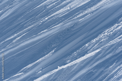 Multiple wind packed snow ridges forming oblique lines in sunshine