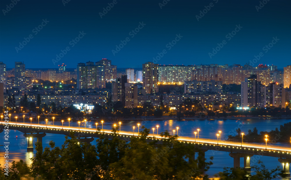 Night Kiev cityscape. Kyiv Left bank skyline with Paton bridge over Dnieper river