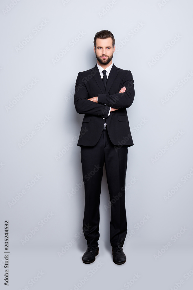 Full size fullbody portrait of virile harsh business person in black suit with tie having his arms crossed, isolated on grey background Full size fullbody portrait of virile harsh business person in black suit with tie having his arms crossed, isolated on grey background