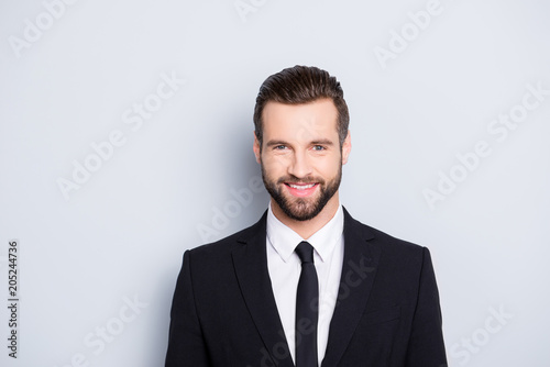Portrait of positive joyful business person with modern hairstyle and elegant outfit, wearing black suit with tie looking at camera, isolated on grey background