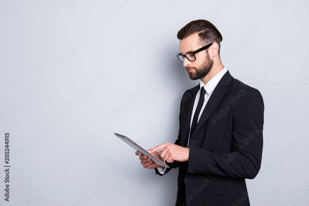 Portrait with copyspace, empty space of busy smart man with modern hairstyle, stubble, having tablet in hands, checking email, chatting with partners over grey background Portrait with copyspace, empty space of busy smart man with modern hairstyle, stubble, having tablet in hands, checking email, chatting with partners over grey background
