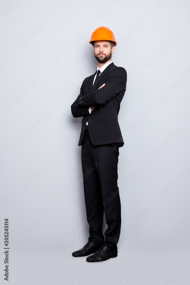 Full length size portrait of attractive beardedstylish investor in hard hat, black tux, tuxedo with tie, isolated on grey background, having his arms crossed Full length size portrait of attractive beardedstylish investor in hard hat, black tux, tuxedo with tie, isolated on grey background, having his arms crossed