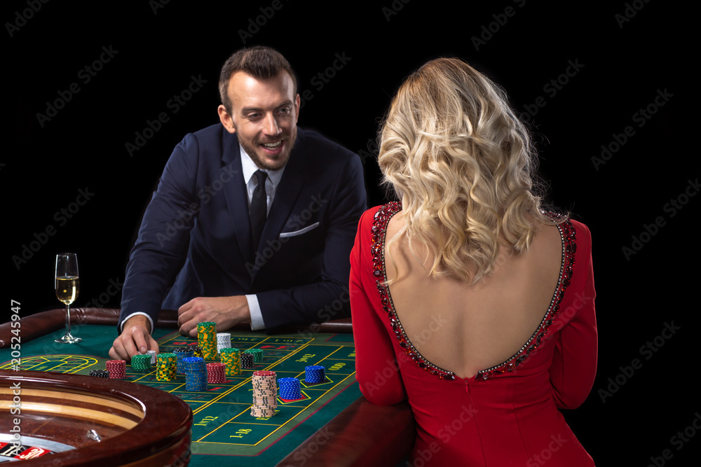 A beautiful young woman and a man are sitting at a roulette table. Casino. A beautiful young woman and a man are sitting at a roulette table. Casino.