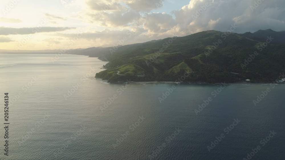 Aerial view of seashore with beach and mountains with sky and clouds at sunset. Philippines, Luzon. View of the ocean with the coastline. Tropical landscape in Asia. Aerial view of seashore with beach and mountains with sky and clouds at sunset. Philippines, Luzon. View of the ocean with the coastline. Tropical landscape in Asia.