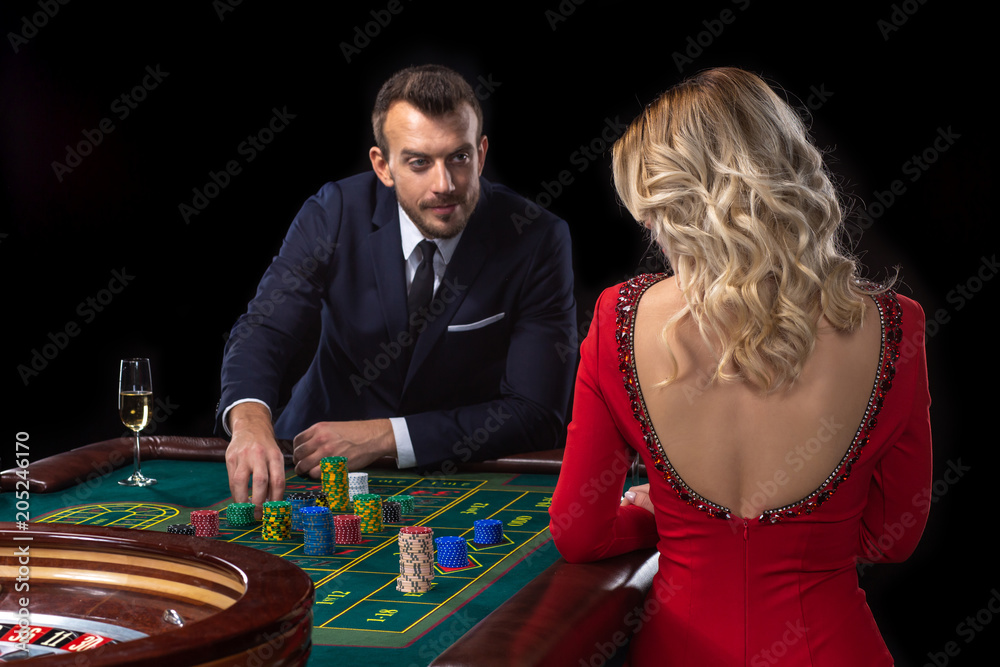 A beautiful young woman and a man are sitting at a roulette table. Casino. A beautiful young woman and a man are sitting at a roulette table. Casino.