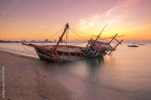 The beautiful twilight scene of fishing boat aground on the beach near the city.