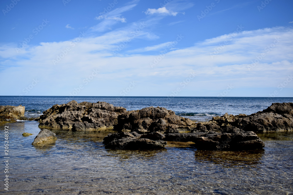 Beautiful view of the rocky coast of the Mediterranean Sea and the blue sky with white clouds Beautiful view of the rocky coast of the Mediterranean Sea and the blue sky with white clouds
