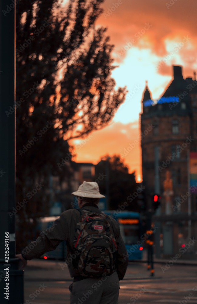 A man with hat is waiting near the traffic light in Stockholm's afternoon or sunset