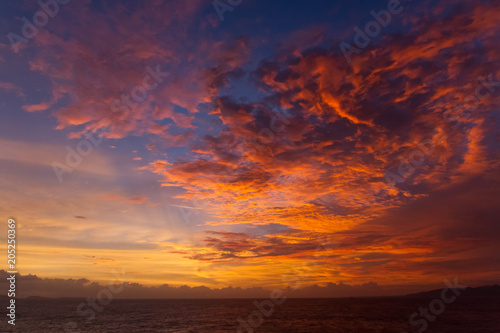 summer sunset colorful sky with dramatic purple red and yellow clouds over picturesque water landscape. Bali, Indonesia.