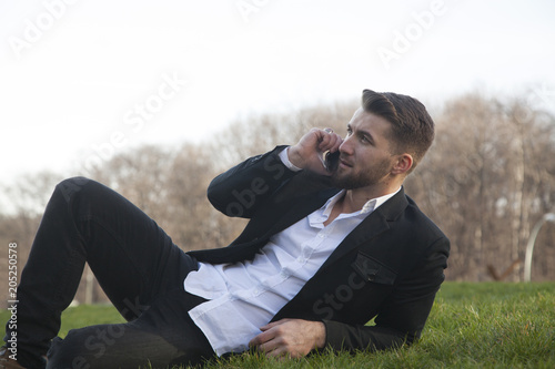 Junger bärtiger Geschäftsmann liegt auf der Wiese und telefoniert © Cara-Foto