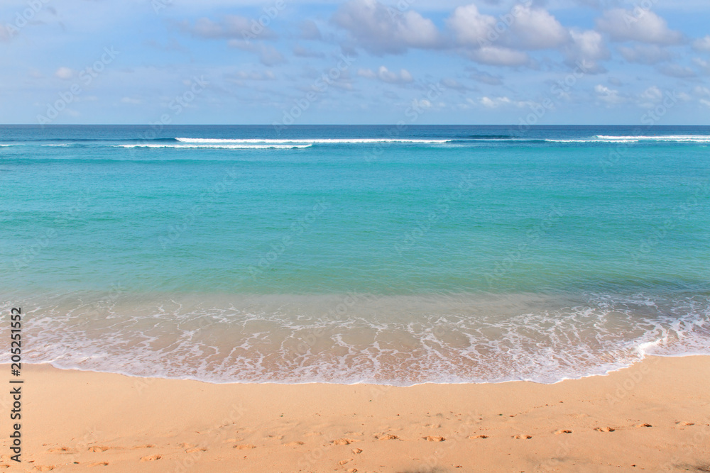 yellow sandy coastline with azure foamy ocean waves on a bright Sunny day. Bali, Indonesia. yellow sandy coastline with azure foamy ocean waves on a bright Sunny day. Bali, Indonesia.