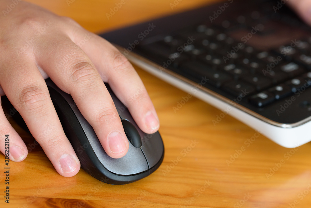Persons hand using a computer mouse on a wooden desk Persons hand using a computer mouse on a wooden desk