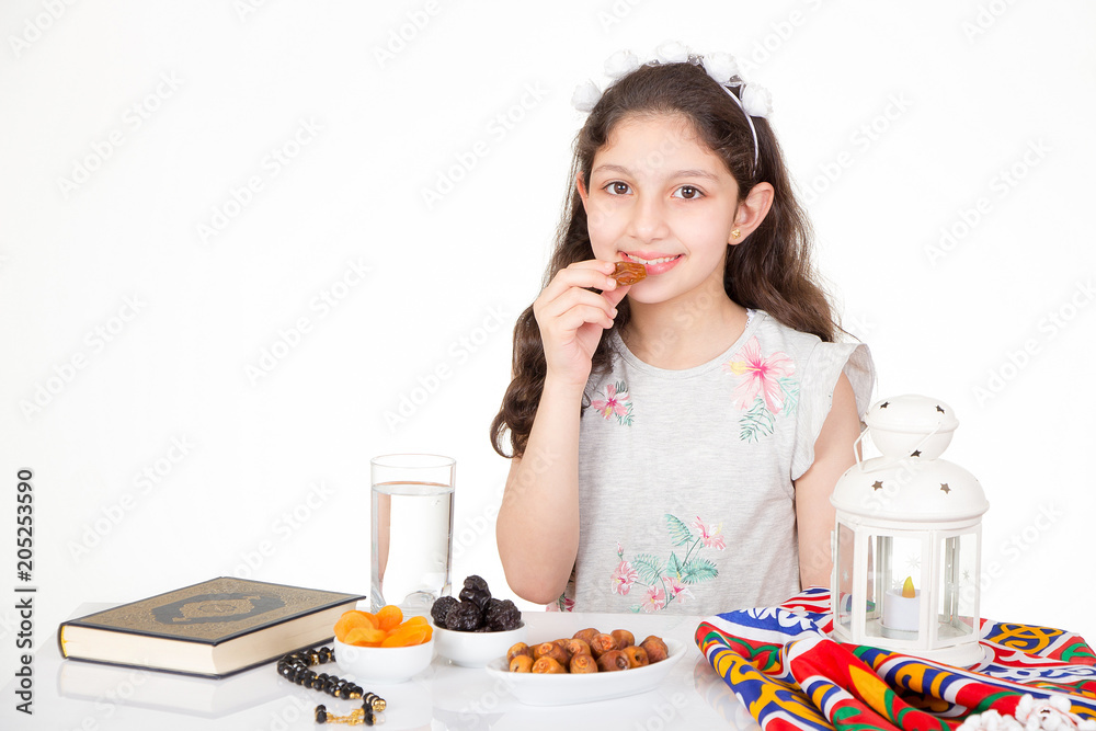Happy young Muslim girl eating dates for iftar - breakfast in holy Ramadan