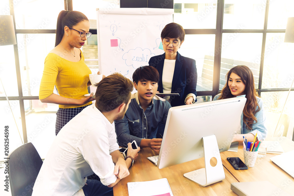 Asian young man business officer explaining internal meeting to his project team in modern office. They are the multi ethnic business person group in casual suit. Project and Business concept. Asian young man business officer explaining internal meeting to his project team in modern office. They are the multi ethnic business person group in casual suit. Project and Business concept.