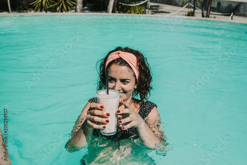 .Young woman on vacation in the gili islands enjoying a fruit juice in a spectacular outdoor swimming pool, relaxing and sunbathing. Travel photography. photo