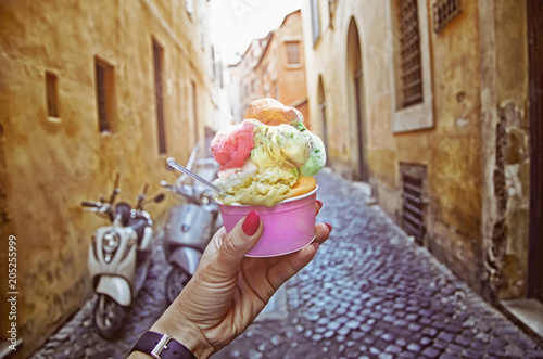 Italian ice - cream cone held in hand on the background of on vintage street atmosphere in Rome , Italy