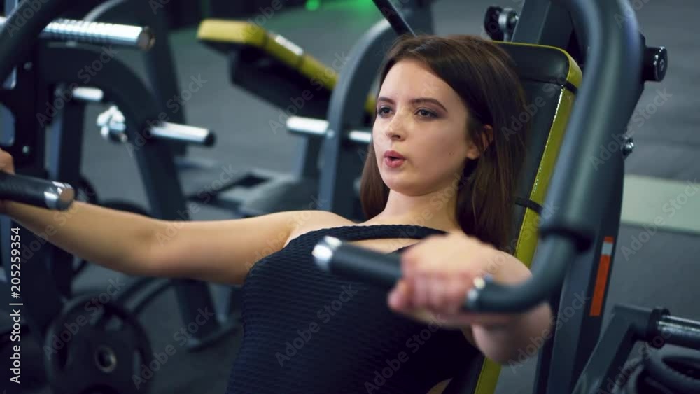 Young girl flexing muscles on gym machine Young girl flexing muscles on gym machine