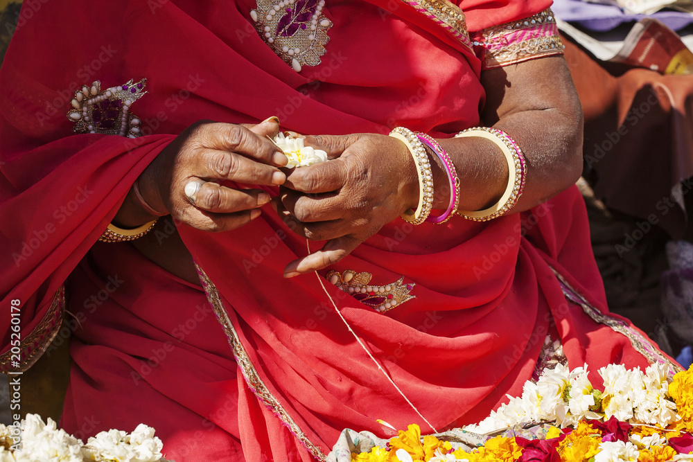 Indian female hands making fresh flower necklace for selling