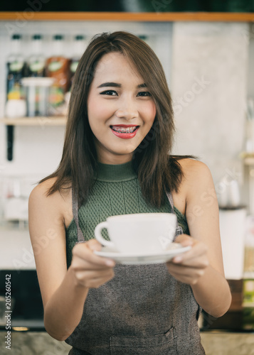 Young woman bartender holding coffee cup in coffee shop