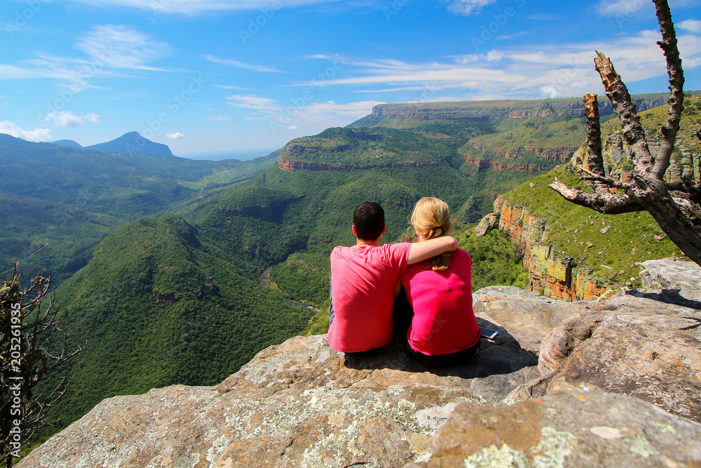 Naklejka premium Couple with red shirts contemplating the Lowveld view along the Blyde River Canyon, Mpumalanga province of South Africa