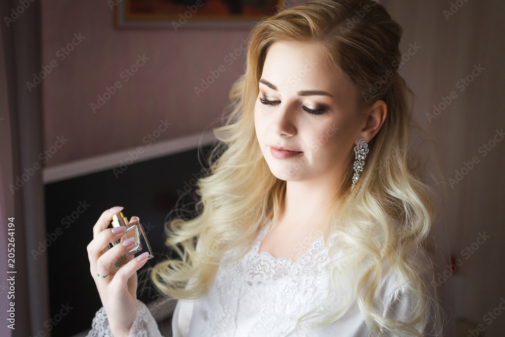 Elegant blonde bride holding in hands and spraying a bottle of luxury fragrant perfume Elegant blonde bride holding in hands and spraying a bottle of luxury fragrant perfume
