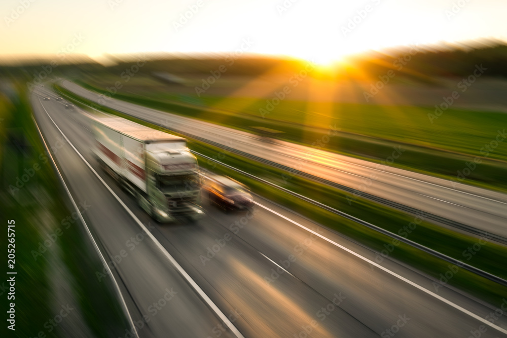 Truck and cars in motion blur on the freeway towards the setting sun. Rush hour on the motorway in Finland - obrazy, fototapety, plakaty 