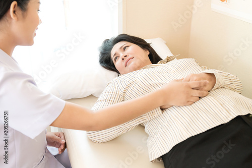 Nurse with patient. Routine health check and holding hand. Female nurse with senior chinese woman.