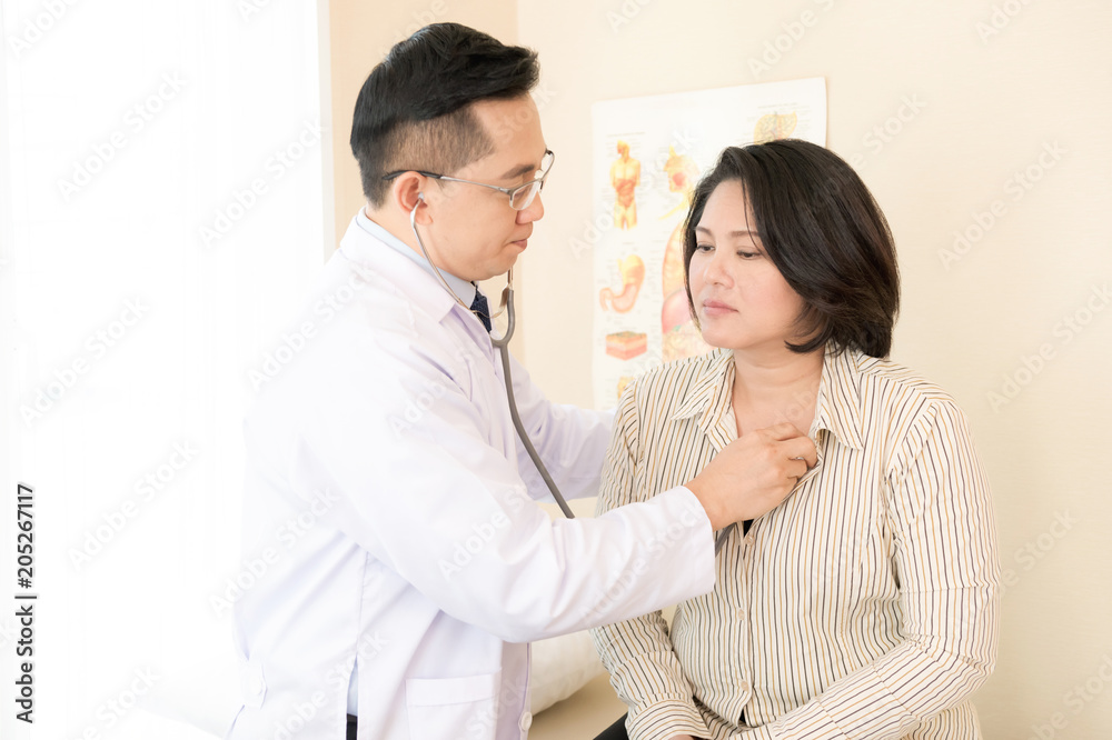 Doctor with patient. Routine health check and checking heart. Male medical doctor with middle age chinese woman. Doctor with patient. Routine health check and checking heart. Male medical doctor with middle age chinese woman.
