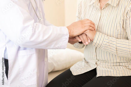 Doctor with patient. Routine health check and holding hands. Male medical doctor with middle age chinese woman.