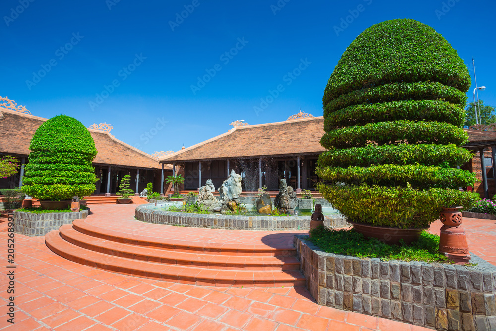 Vietnamese courtyard with trees, a fountain and houses covered with