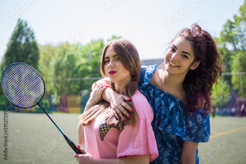 Girls girlfriends play badminton on the football field on a sunny day