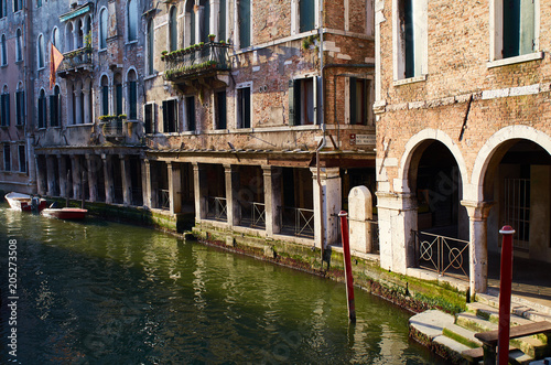 Afternoon sunlight illuminates a portico beside a Venetian canal