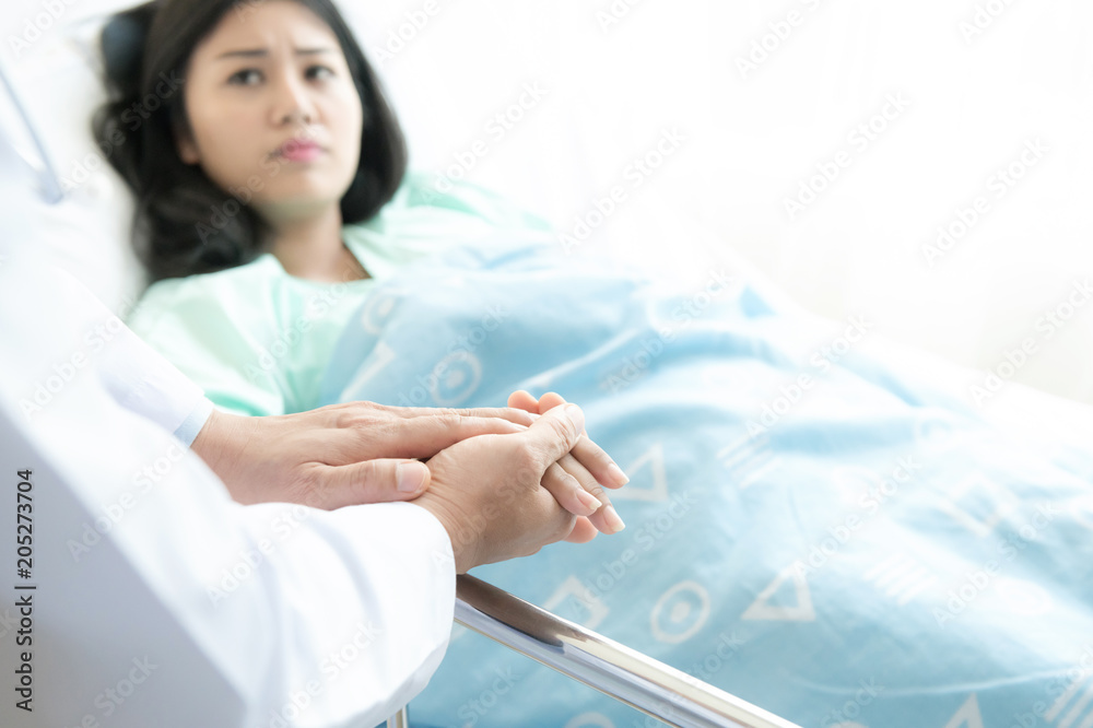 Doctor with patient. Routine health check and holding hands. Male medical doctor with young chinese woman. Doctor with patient. Routine health check and holding hands. Male medical doctor with young chinese woman.