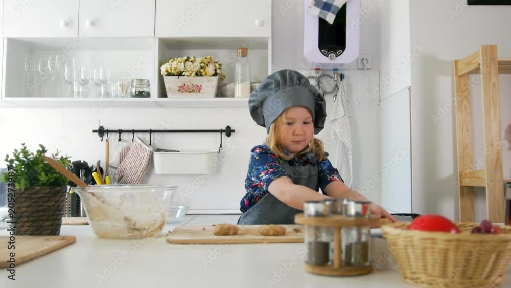 Preschool girl baker puts biscuits on a baking sheet Preschool girl baker puts biscuits on a baking sheet