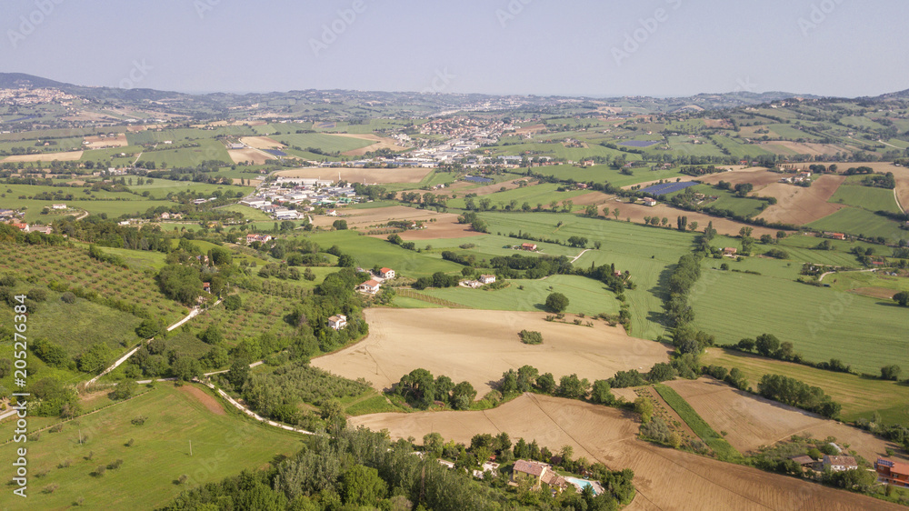 Aerial view of the countryside between Tuscany and Marche in Italy during a beautiful sunny day in summer. The fields are cultivated and the hills are rich in trees and forests.