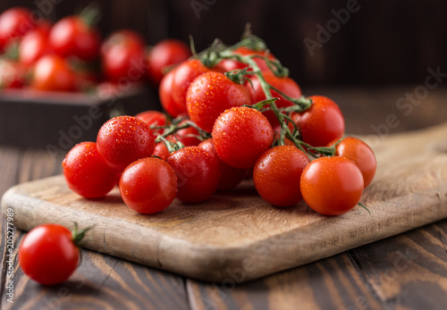 Small red cherry tomatoes on rustic background. Cherry tomatoes on the vine