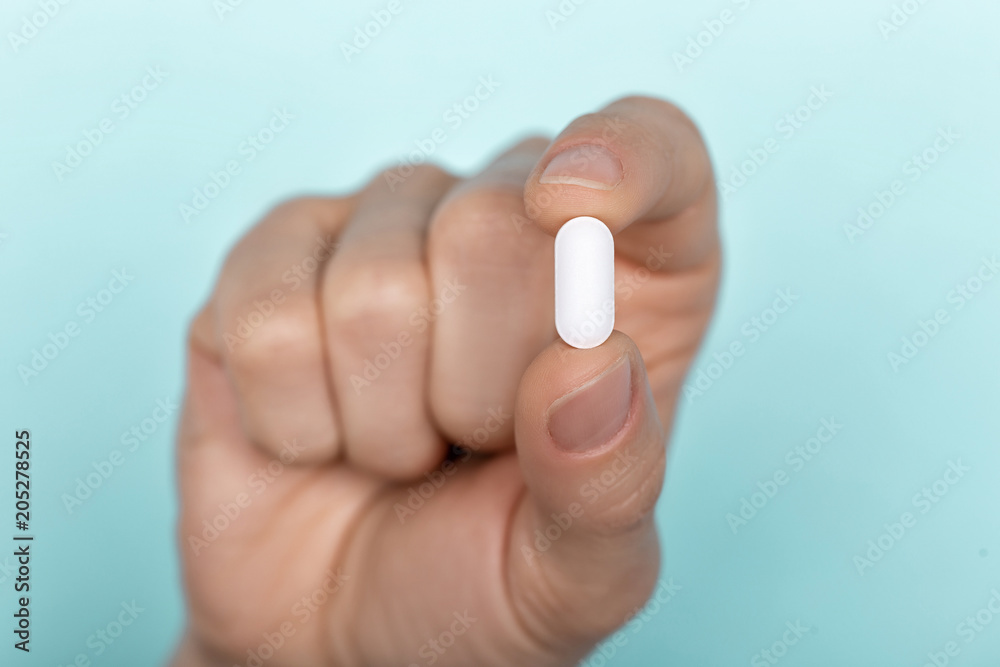 pill in man's hand on white background